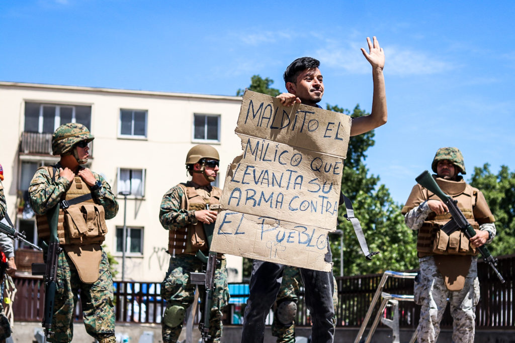 Un jove protesta davant un grup de militars xilens fortament armats