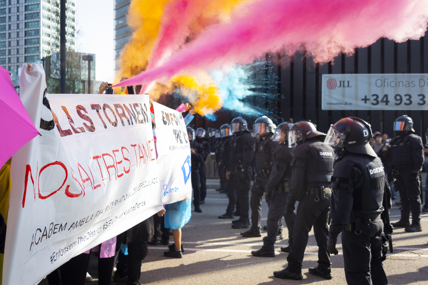 Manifestants llencen pols de colors al cordó policial que bloqueja l'accés a la Fira de Barcelona